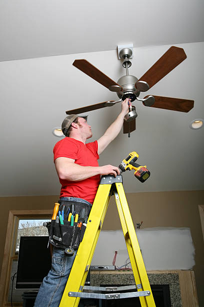 Electrician installing energy-saving ceiling fan on home addition job.